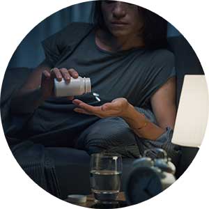 A woman sits in bed and takes medication